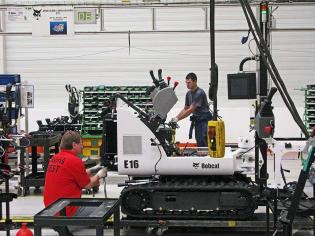 Pracownicy fabryki montujący minikoparkę, model E16