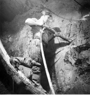 Korytarz prowadzący do komory rozjazdowej. Widoczny górnik pracujacy przy podziemnych odwiertach. 1956 r. Fot. Narodowe Archiwum Cyfrowe