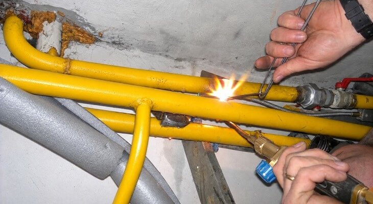 Spawanie stalowej instalacji gazowej pod stropem piwnicy w bloku 