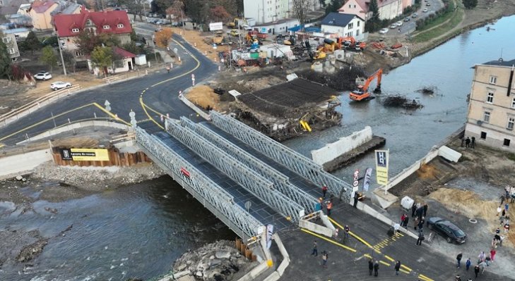 Obecnie w Głuchołazach funkcjonują dwa tymczasowe, wykonane przez wojsko, mosty DMS-65. Obok zerwana konstrukcja budowanej przeprawy. Fot. GDDKiA